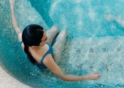 Aerial view of a woman in a blue swimsuit lounging in a swimming pool, capturing a serene moment.